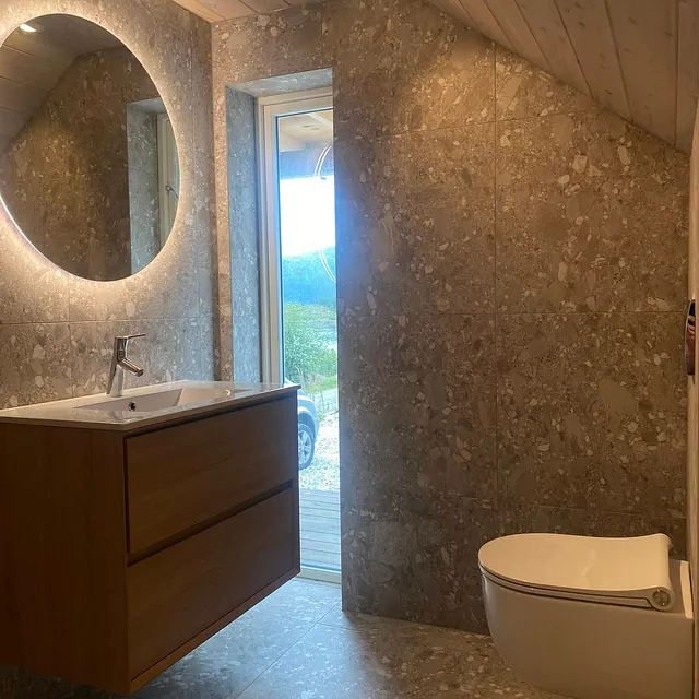 Moderne bad med rundt speil og vegghengt toalett